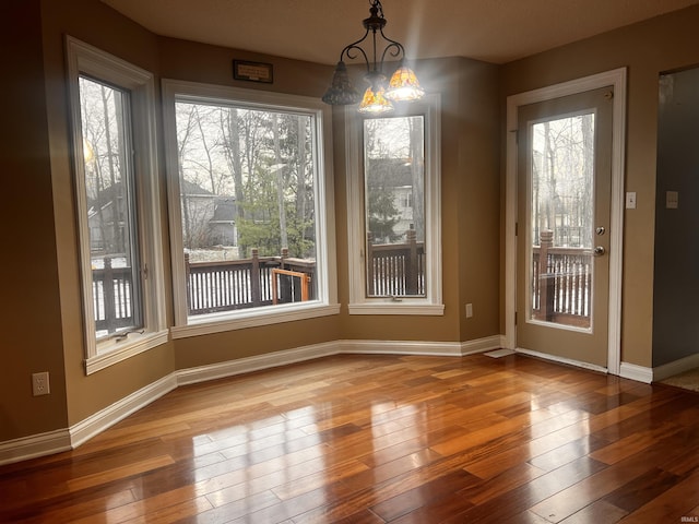 unfurnished dining area with hardwood / wood-style floors and a notable chandelier