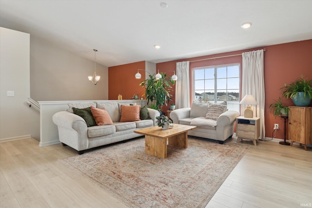 living room with vaulted ceiling, an inviting chandelier, and light hardwood / wood-style flooring