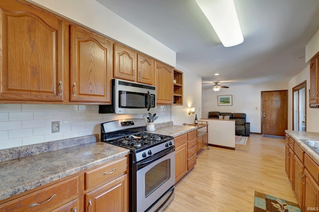 kitchen featuring appliances with stainless steel finishes, light wood-type flooring, ceiling fan, and decorative backsplash