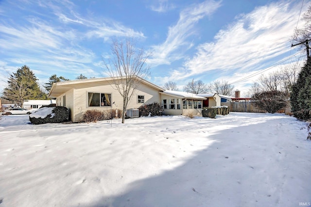 snow covered rear of property with central AC unit