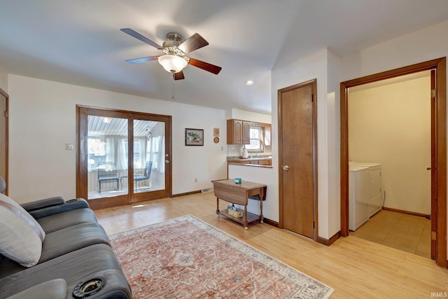 living room with ceiling fan, washing machine and clothes dryer, and light wood-type flooring