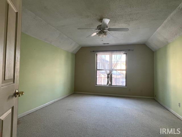 additional living space featuring lofted ceiling, ceiling fan, light carpet, and a textured ceiling