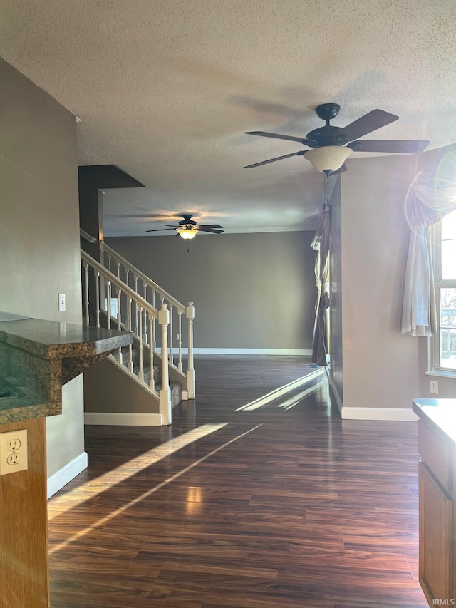 unfurnished living room with dark hardwood / wood-style flooring, ceiling fan, and a textured ceiling