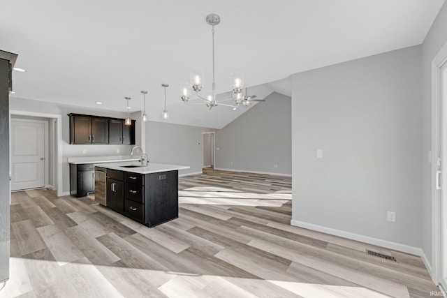 kitchen featuring pendant lighting, sink, a chandelier, dark brown cabinetry, and a center island with sink