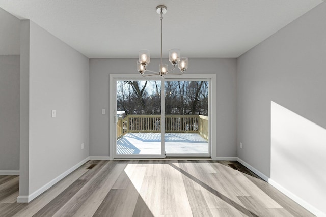 unfurnished dining area featuring wood-type flooring and a notable chandelier