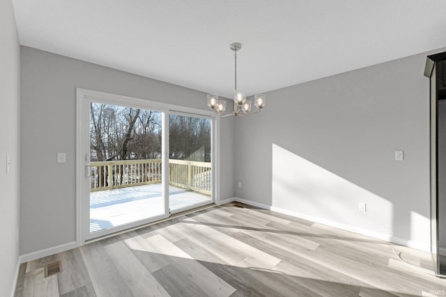 unfurnished dining area featuring an inviting chandelier and light wood-type flooring