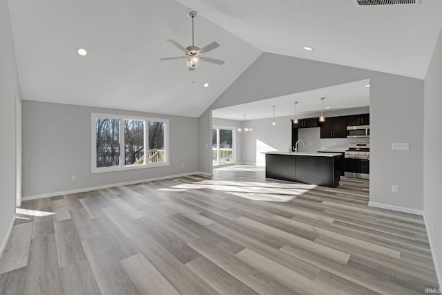 unfurnished living room with ceiling fan, high vaulted ceiling, sink, and light wood-type flooring