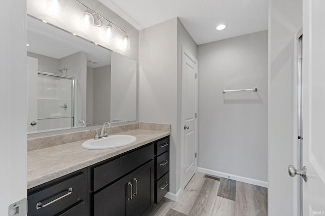 bathroom featuring vanity, hardwood / wood-style flooring, and a shower with door