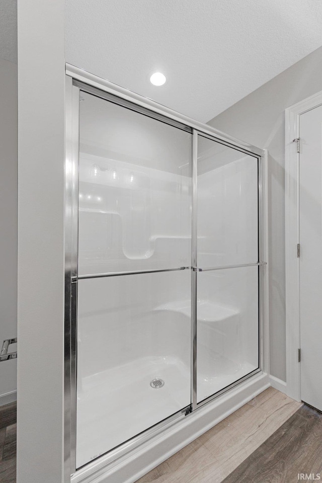 bathroom with hardwood / wood-style flooring and a shower with door