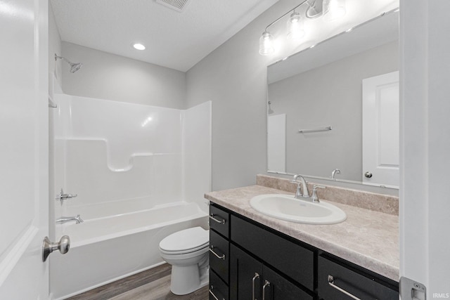 full bathroom with hardwood / wood-style floors, shower / bathtub combination, vanity, toilet, and a textured ceiling