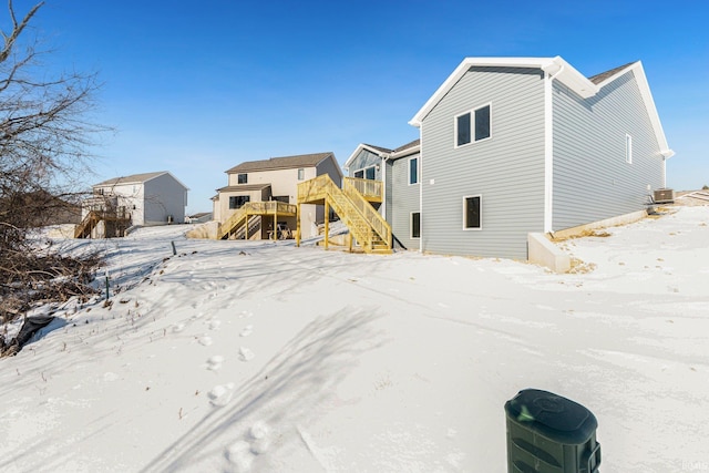 snow covered property with a wooden deck and central AC