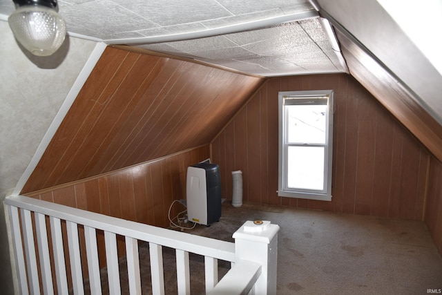 additional living space featuring vaulted ceiling, wood walls, and carpet flooring