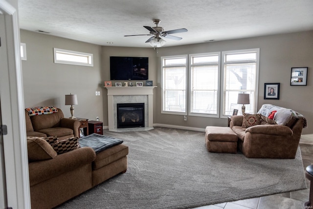 carpeted living room with ceiling fan, a textured ceiling, and a high end fireplace