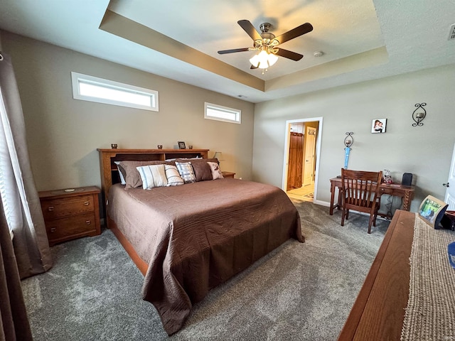 carpeted bedroom featuring ensuite bath, a raised ceiling, and ceiling fan