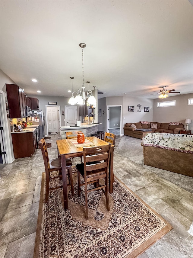 dining space featuring sink and ceiling fan with notable chandelier