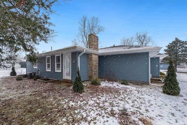 snow covered back of property featuring central air condition unit