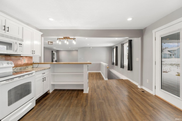 kitchen featuring dark hardwood / wood-style floors, white cabinets, light stone counters, kitchen peninsula, and white appliances