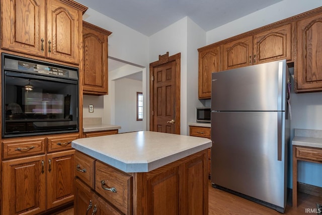 kitchen with stainless steel appliances, light hardwood / wood-style floors, and a kitchen island