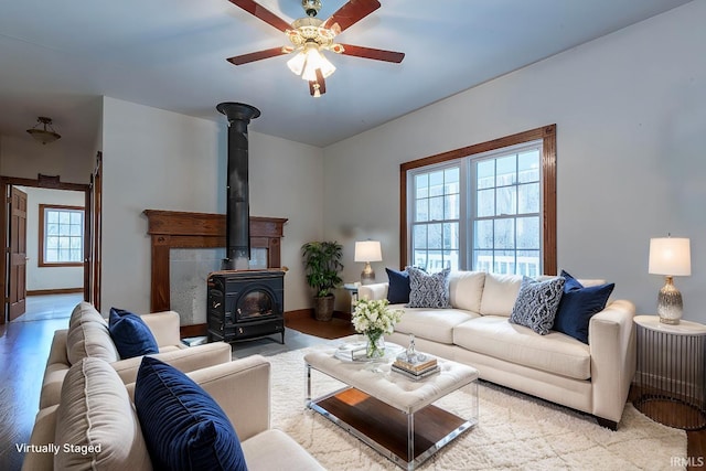 living room with light hardwood / wood-style flooring, a wealth of natural light, ceiling fan, and a wood stove