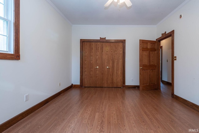 unfurnished bedroom featuring hardwood / wood-style floors, crown molding, a closet, and ceiling fan