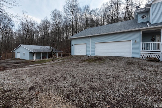 view of property exterior featuring a carport, a garage, an outdoor structure, and covered porch