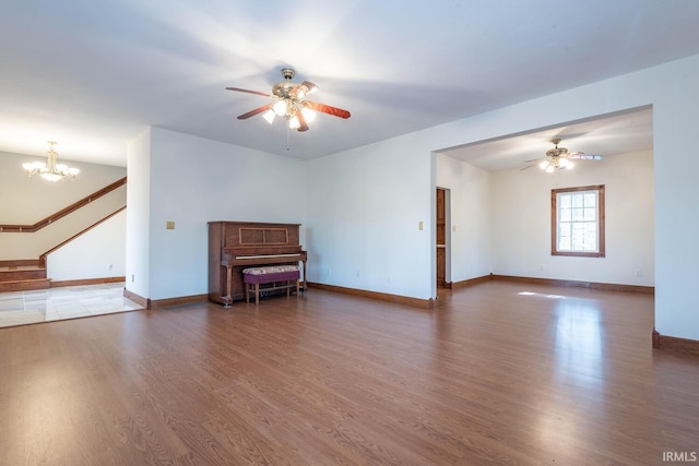 unfurnished room featuring dark wood-type flooring and ceiling fan with notable chandelier