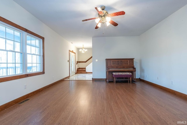 unfurnished room with hardwood / wood-style flooring and ceiling fan with notable chandelier