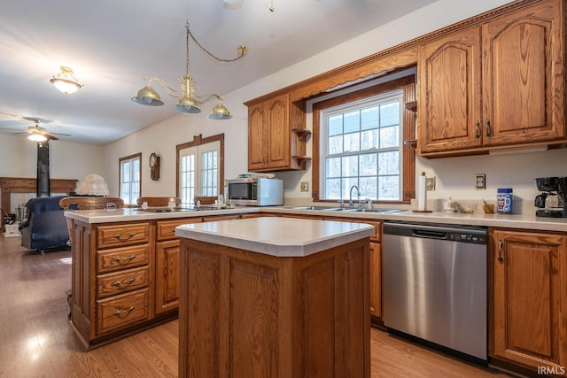 kitchen with appliances with stainless steel finishes, decorative light fixtures, a center island, and light hardwood / wood-style floors