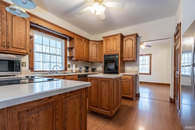 kitchen with sink, a center island, a wealth of natural light, hardwood / wood-style floors, and black appliances