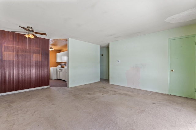 unfurnished living room featuring washer and clothes dryer, light colored carpet, and ceiling fan