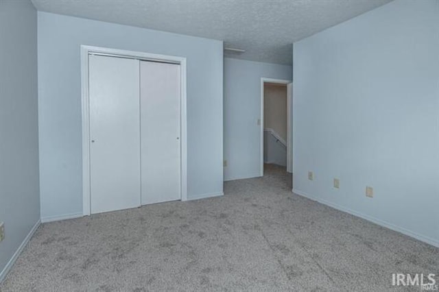 unfurnished bedroom featuring light colored carpet, a closet, and a textured ceiling