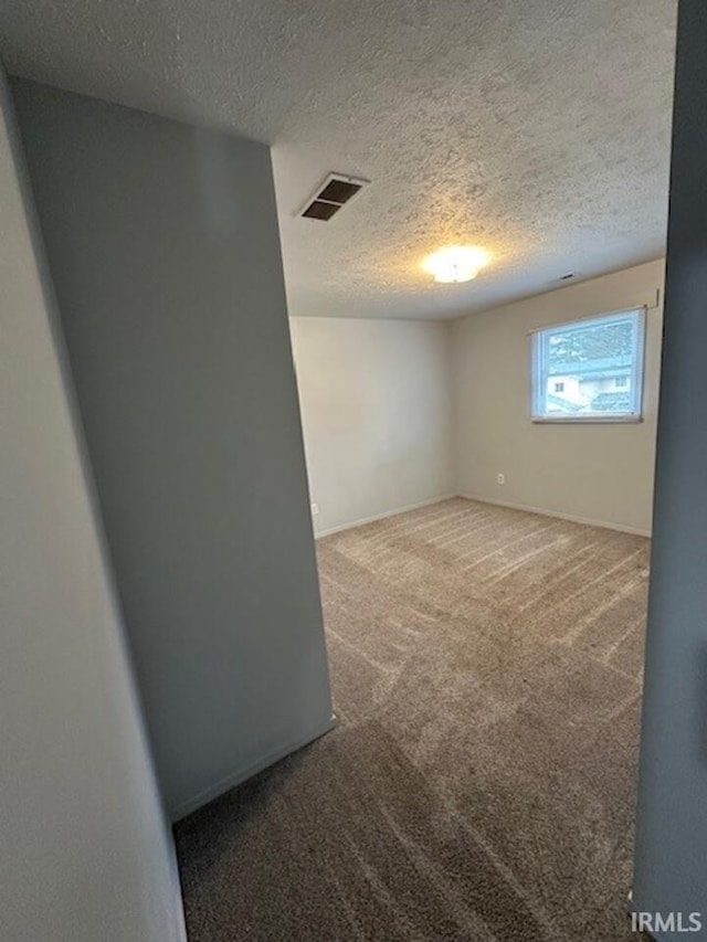 unfurnished room featuring a textured ceiling and carpet flooring