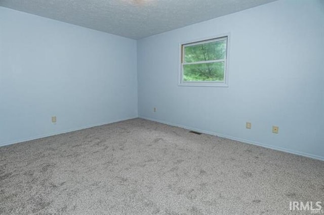 carpeted empty room with a textured ceiling