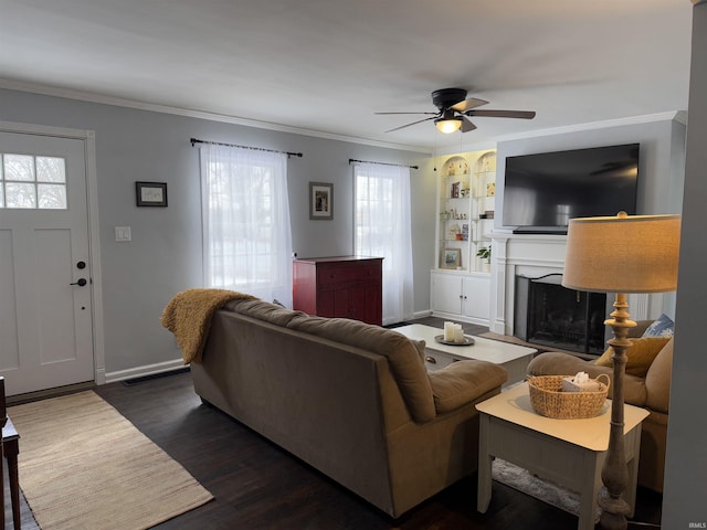 living room featuring ornamental molding, dark wood-type flooring, ceiling fan, and built in shelves