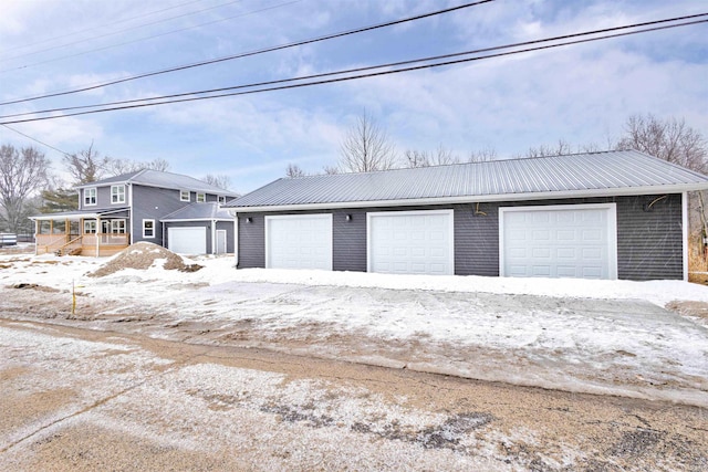 snow covered garage featuring covered porch