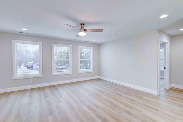 empty room with a wealth of natural light, light hardwood / wood-style flooring, and ceiling fan