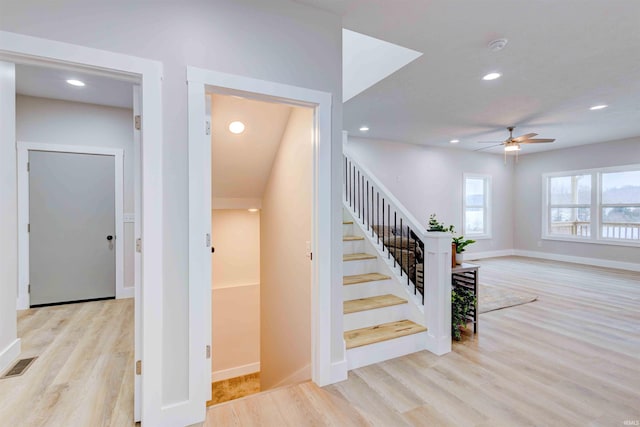 stairway with hardwood / wood-style floors and ceiling fan