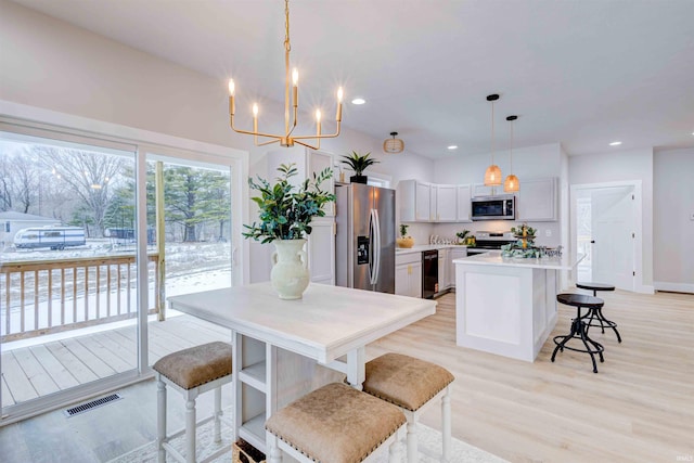 kitchen with a breakfast bar, pendant lighting, white cabinetry, a center island, and stainless steel appliances