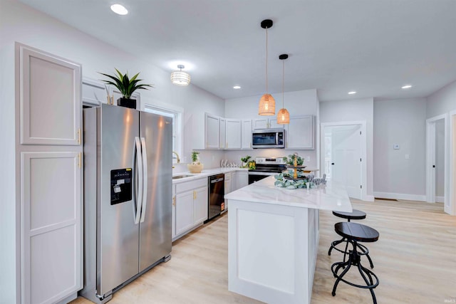 kitchen featuring sink, white cabinetry, hanging light fixtures, a kitchen island, and stainless steel appliances