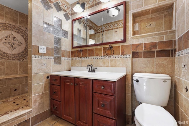 bathroom featuring tile patterned floors, vanity, toilet, and tile walls