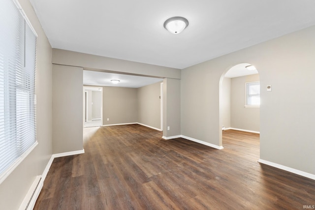 unfurnished room with dark hardwood / wood-style flooring and a baseboard heating unit