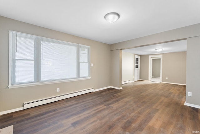 empty room featuring baseboard heating and dark hardwood / wood-style flooring