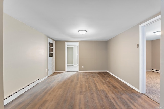 spare room featuring a baseboard heating unit and dark hardwood / wood-style floors