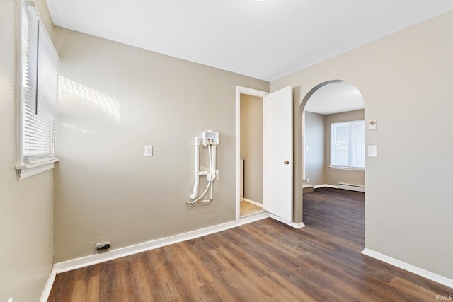 empty room with a baseboard heating unit and dark wood-type flooring