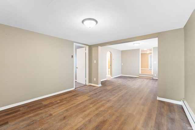 empty room featuring a baseboard heating unit and dark wood-type flooring