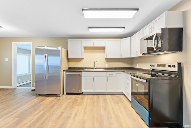 kitchen featuring appliances with stainless steel finishes, sink, white cabinets, a baseboard heating unit, and light wood-type flooring