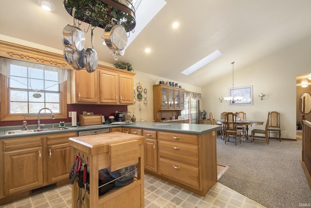 kitchen with sink, hanging light fixtures, a kitchen island, light colored carpet, and vaulted ceiling with skylight