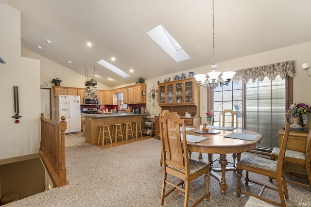 dining room with an inviting chandelier, a skylight, plenty of natural light, and high vaulted ceiling