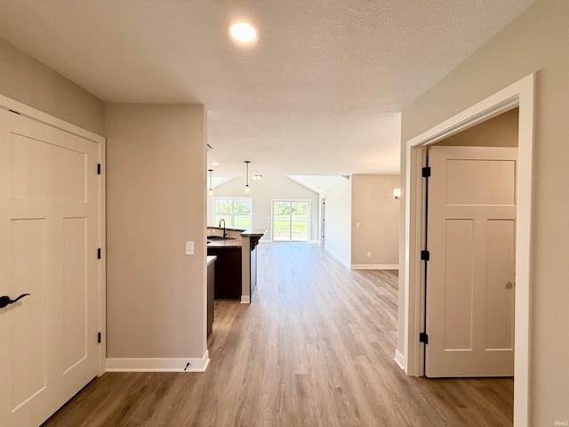 2360 Serenity Ct, Auburn, IN 46706 - hall with light wood finished floors, baseboards, vaulted ceiling, and a sink