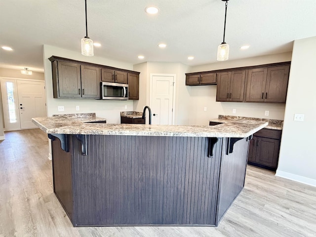 2360 Serenity Ct, Auburn, IN 46706 - kitchen featuring stainless steel microwave, dark brown cabinets, light wood finished floors, hanging light fixtures, and recessed lighting